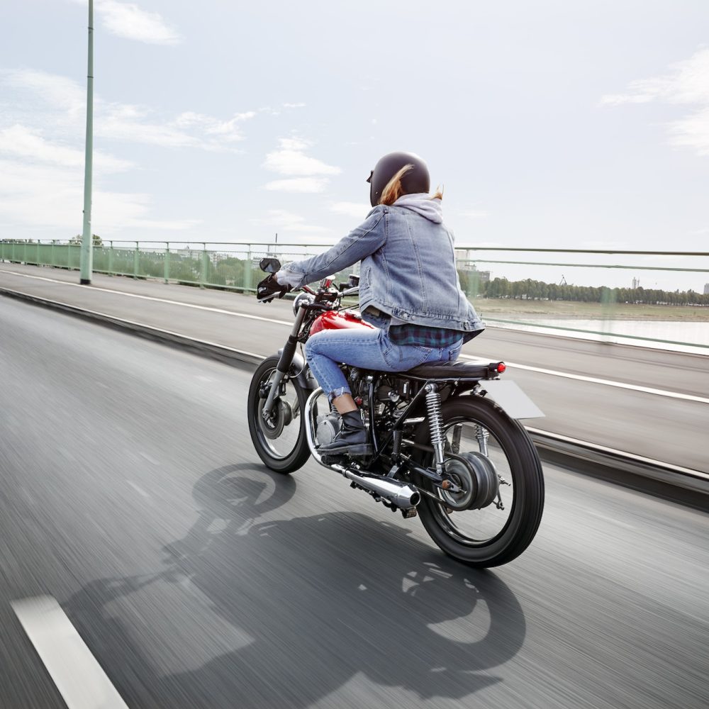 Young woman riding motorcycle on bridge